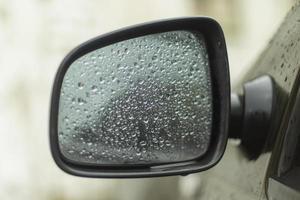 espejo retrovisor mojado. gotas sobre vidrio. transporte bajo la lluvia. foto