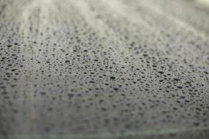 Drops of water on black surface. Car parts in rain. photo