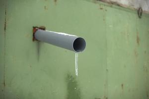 Pipe for draining water. Ice on pipe. Drainage of water from building. photo