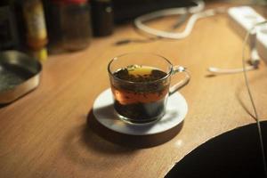 Tea in clear cup. Drink is hot. Tea leaves in boiling water. photo