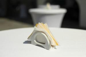 Yellow and white napkins in a white porcelain napkin on a white table, close-up. photo