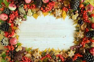 Frame from colorful autumn leaves, mushrooms, rose hips, rowanberry, apples, nuts, cones and cookies on the wooden background. Fall background. photo