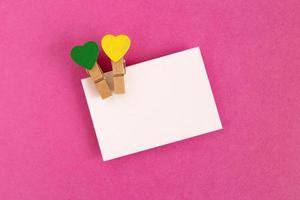 White sheet with green and yellow pins on the pink background for Valentine Day. Copy space. photo