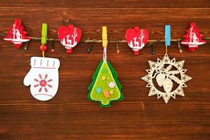 Wooden and felt Christmas decorations and Christmas lights on a rope on the brown wooden background, top view. photo