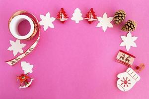 Top view on the frame from red and white Christmas decorations and pine cones on the pink background with copy space. photo