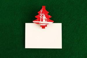 White sheet with red and white pin on the green background for Christmas greetings. Copy space. photo