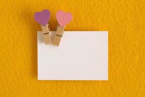 White sheet with pink and purple pins on the yellow background for Valentine Day. Copy space. photo