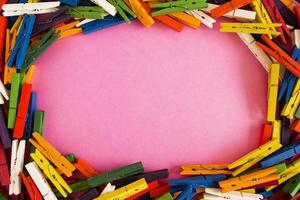 marco de alfileres de colores de madera sobre el fondo rosa con espacio de copia. foto
