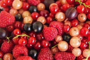 Mixed summer berries - raspberry, blackcurrant, redcurrant, white currant, gooseberry, cherry - on the white wooden background, top view. photo