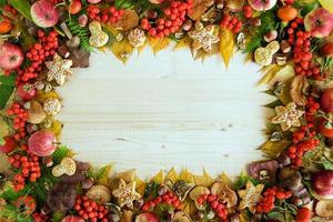 marco de coloridas hojas de otoño, champiñones, escaramujos, serbas, manzanas, nueces y galletas en el fondo de madera. fondo de caída. foto