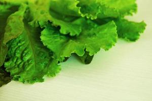 las hojas de ensalada verde sobre el fondo blanco de madera. foto