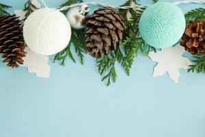 Christmas flat lay composition with fir branches, pine cones, decorations and blue and white Christmas lights on the blue background with copy space. photo