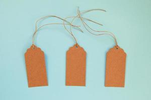 Three brown blank paper price tags or labels set on the blue background, top view. photo