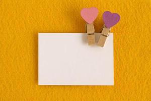 White sheet with pink and purple pins on the yellow background for Valentine Day. Copy space. photo