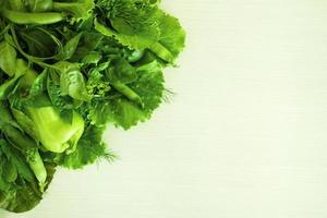 verdura verde - ensalada, albahaca, eneldo, acedera, guisantes, pimiento, pepino - sobre el fondo blanco de madera, vista superior. foto