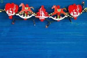 adornos navideños de madera roja y blanca y luces navideñas en el fondo de madera azul, vista superior. foto