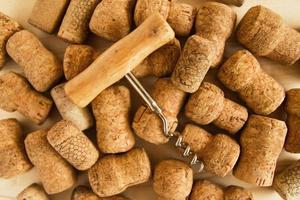 Wine corks and corkscrew on the wooden background, top view. photo