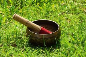 Tibetian singing bowl with wooden stick on the grass. photo