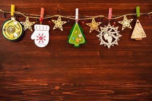 Wooden and felt Christmas decorations and Christmas lights on a rope on the brown wooden background, top view. photo