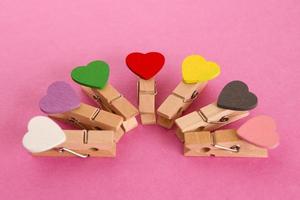 Wooden pins with colorful hearts on the pink background. Decorations for Valentine Day. photo