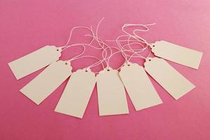 White blank paper price tags or labels set on the pink background. photo