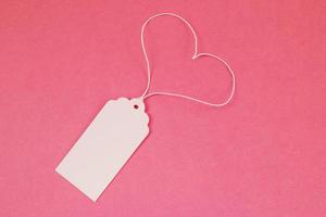 White blank paper price tag or label on the pink background, top view. photo