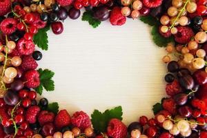 Frame from mixed summer berries on the white wooden background, top view. photo