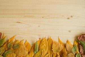 Border from autumn dry colorful leaves on the wooden background, top view. photo