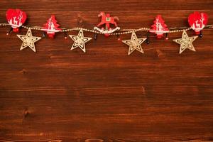 Red and white wooden Christmas decorations and Christmas lights on the brown wooden background, top view. photo