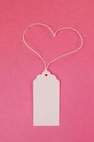 White blank paper price tag or label on the pink background, top view. photo