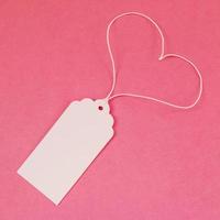 White blank paper price tag or label on the pink background, top view. photo