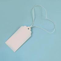 White blank paper price tag or label on the blue background, top view. photo