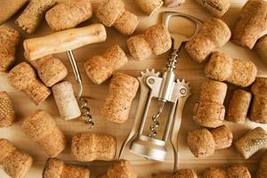 A lot of wine corks and two corkscrews on the wooden background, top view. photo