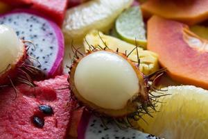 Mixed ripe and fresh fruits closeup for colorful background. Dragon fruit, pineapple, papaya, lime, mango, pomelo, rambutan, watermelon. photo