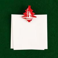 Two white sheet with red and white pin on the green background for Christmas greetings. Copy space. photo