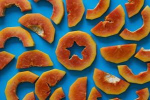 Pieces of orange papaya on blue background. photo