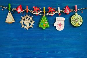 adornos navideños de madera y fieltro y luces navideñas en una cuerda sobre el fondo de madera azul, vista superior. foto