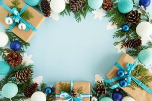 Top view on frame from Christmas decorations, gift boxes, fir branches, pine cones and Christmas lights on the blue background with copy space. photo