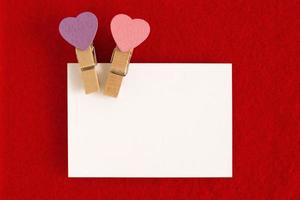 White sheet with pink and purple pins on the red background for Valentine Day. Copy space. photo