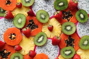 Las frutas y bayas mixtas maduras y frescas se cierran para el fondo. fruta del dragón, piña, papaya, kiwi, fresa. foto
