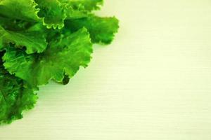 las hojas de ensalada verde sobre el fondo blanco de madera, vista superior. foto