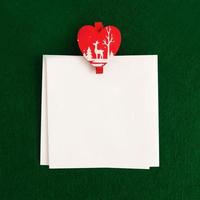 Two white sheet with red and white wooden pin on the green background for Christmas greetings. Copy space. photo