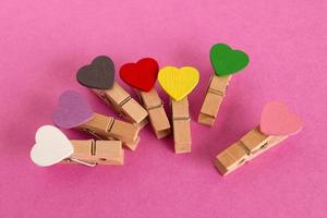 Wooden pins with colorful hearts on the pink background. Decorations for Valentine Day. photo