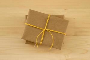 Two gift boxes wrapped of craft paper and yellow ribbon on the wooden background, top view. photo