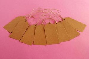 Brown blank paper price tags or labels set on the pink background. photo