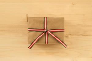 Gift box wrapped of craft paper and colorful ribbon on the wooden background, top view. photo