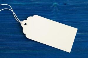 White blank paper price tag or label set on the blue wooden background, closeup. photo