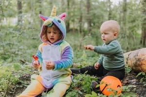 two children walk in the woods with a basket of Halloween candy photo