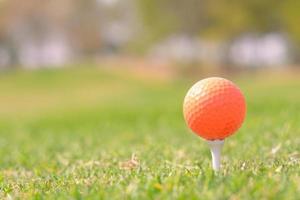 A closeup shot of an orange golf ball in a course photo