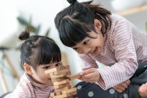 hermana asiática jugando pilas de madera en casa foto